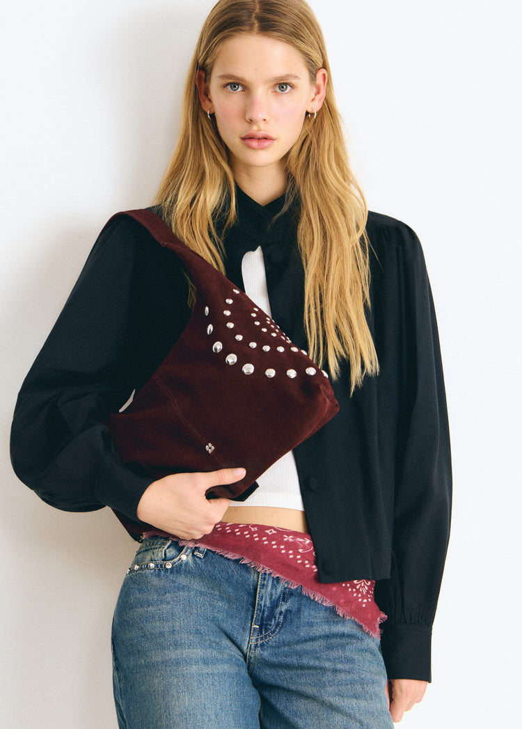 Bolso de hombro marrón con tachas espiral luciendo su frente sobre modelo