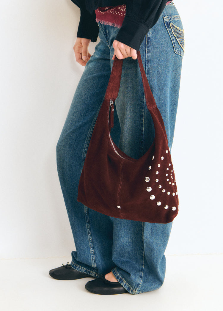 Bolso de hombro marrón con tachas espiral luciendo su perfil lateral sobre modelo
